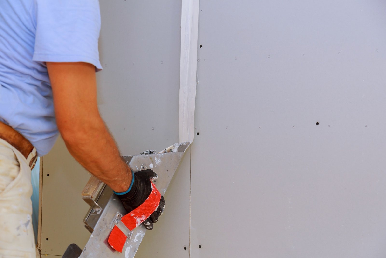 Worker working with putty and spatula work aligns with wall